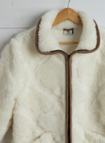 wełniana kurtka w białym kolorze z brązowym zamkiem i lamówką