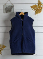 granatowa kamizelka z kapturem z kieszeniami na tle białej ściany z elementami dekoracyjnymi