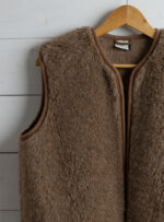 brązowa kamizelka wełniana na wieszaku na tle białej ściany