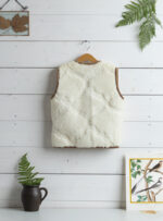 tył wełnianej kamizelki w kolorze ecru na wieszaku z brązowym wykończeniem, w tle ściana obita drewnem i dekoracje