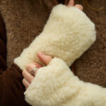 mitenki ecru z wełny na tle brązowej kamizelki wełnianej