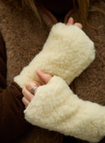 mitenki ecru z wełny na tle brązowej kamizelki wełnianej