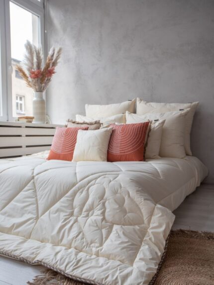 Kołdra z wełny merynos całoroczna w naturalnym kolorze na łóżku, pikowany wzór owcy