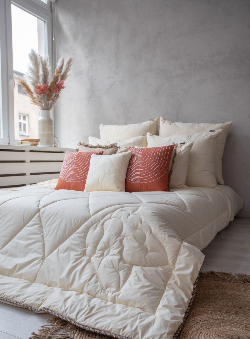 Kołdra z wełny merynos całoroczna w naturalnym kolorze na łóżku, pikowany wzór owcy