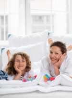 Mama i syn leżą na łóżku z poduszkami, bawią się kolorowymi klockami