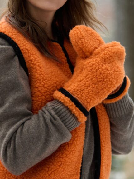Kobieta nosząca pomarańczową kamizelkę i pomarańczowe rękawice z wełny na tle zimowego krajobrazu