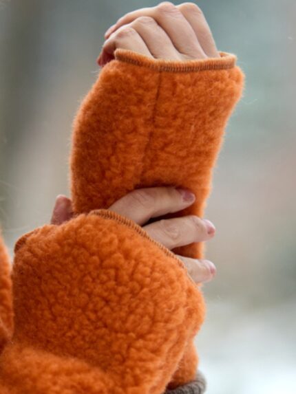 Pomarańczowe mitenki z wełny na dłoniach