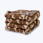 Złożony brązowy koc z wełny we wzór chmurek.