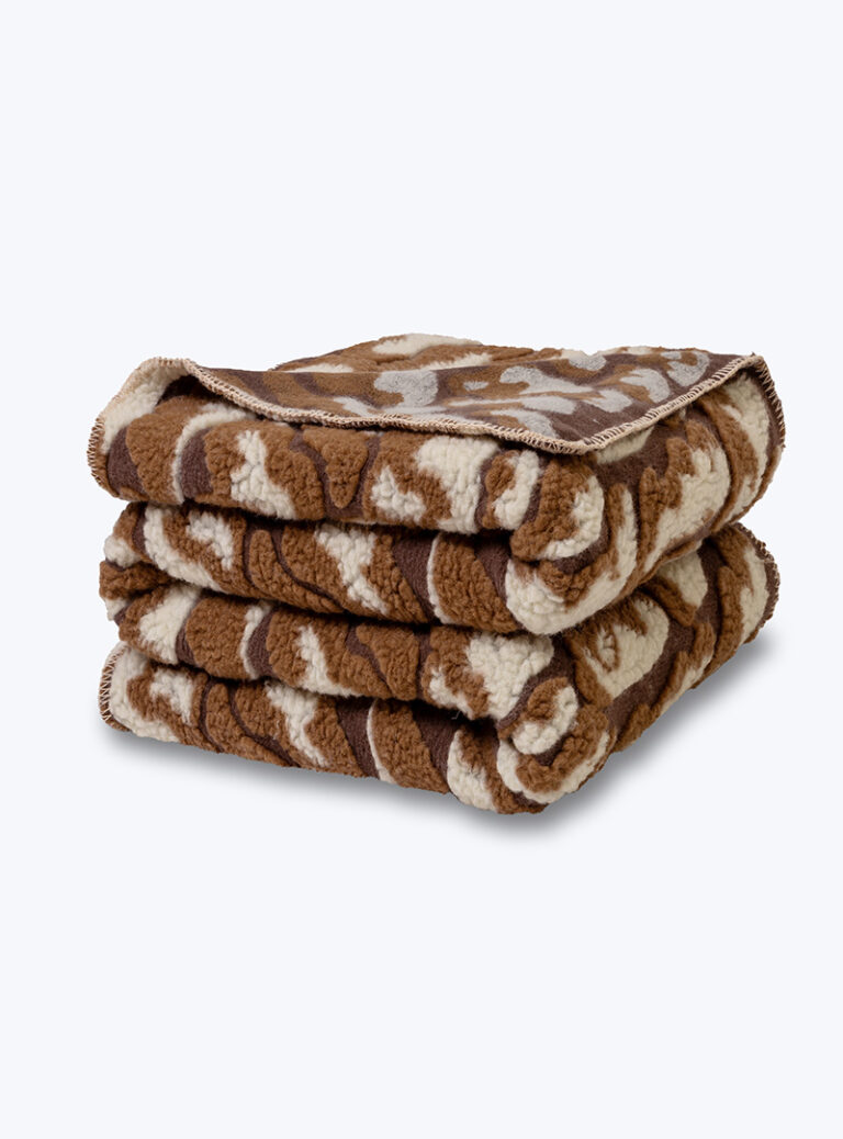 Złożony brązowy koc z wełny we wzór chmurek.