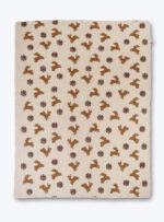 beżowy koc z brązowym wzorem w jelenie i gwiazdki na neutralnym tle