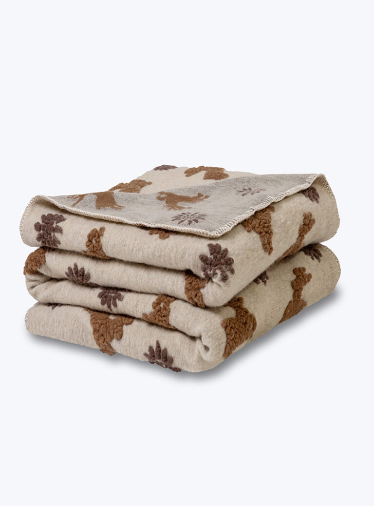 Złożony koc wełniany beżowy z brązowymi wzorami na neutralnym tle