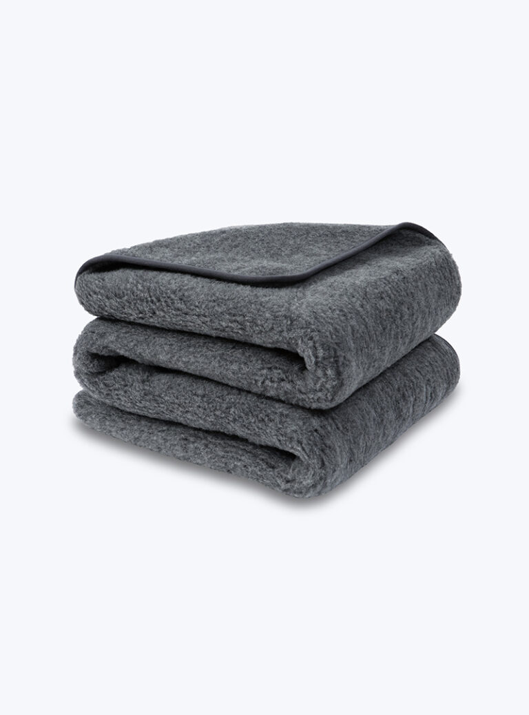 Grafitowy koc z wełny ułożony na sobie na neutralnym tle