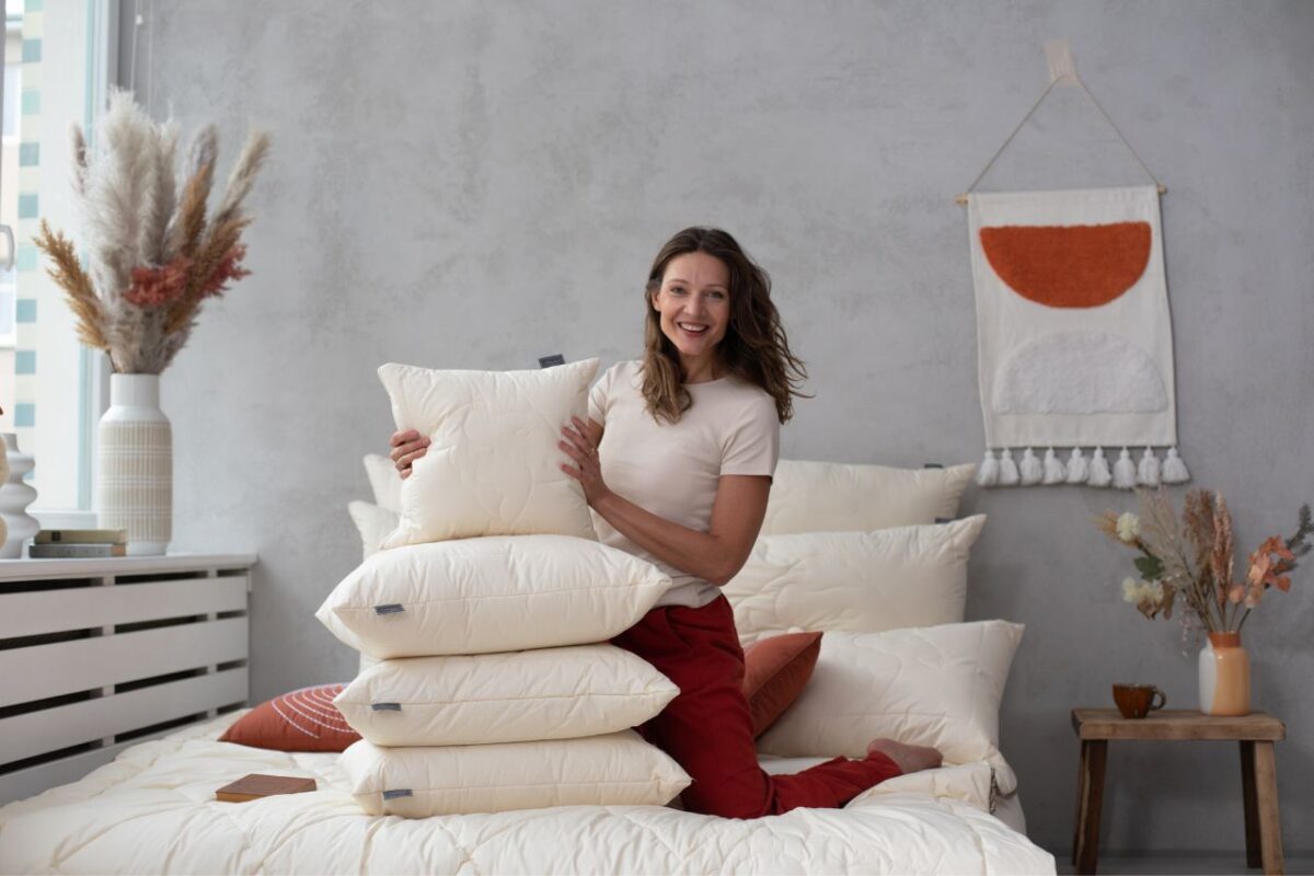 Poduszka z wełny merino w naturalnym kolorze, model prezentowany w jasnej sypialni