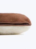 brązowo biała poduszka z wełny z zamkiem błyskawicznym na neutralnym tle