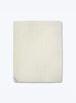 Wełniany ochraniacz na materac na neutralnym tle.