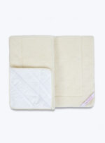 beżowa kołdra z białą poduszką na neutralnym tle