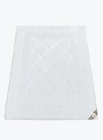 Biały ochraniacz na materac z pikowaniem i wytłoczonym wzorem na tle neutralnym
