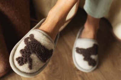 beżowe kapcie z brązowym wzorem w kształcie jelonka na drewnianej podłodze