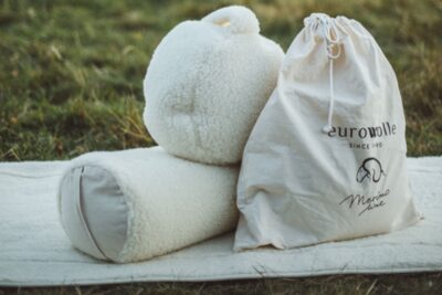 biała akcesoria do jogi z wełny, obok torby, na tle trawy