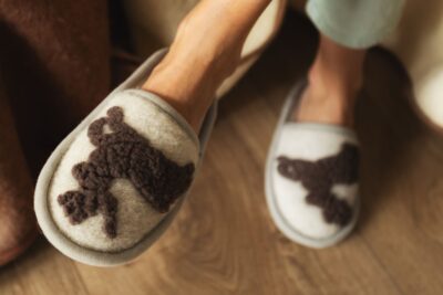 szare kapcie z brązowym wzorem jelonka na tle brązowej podłogi