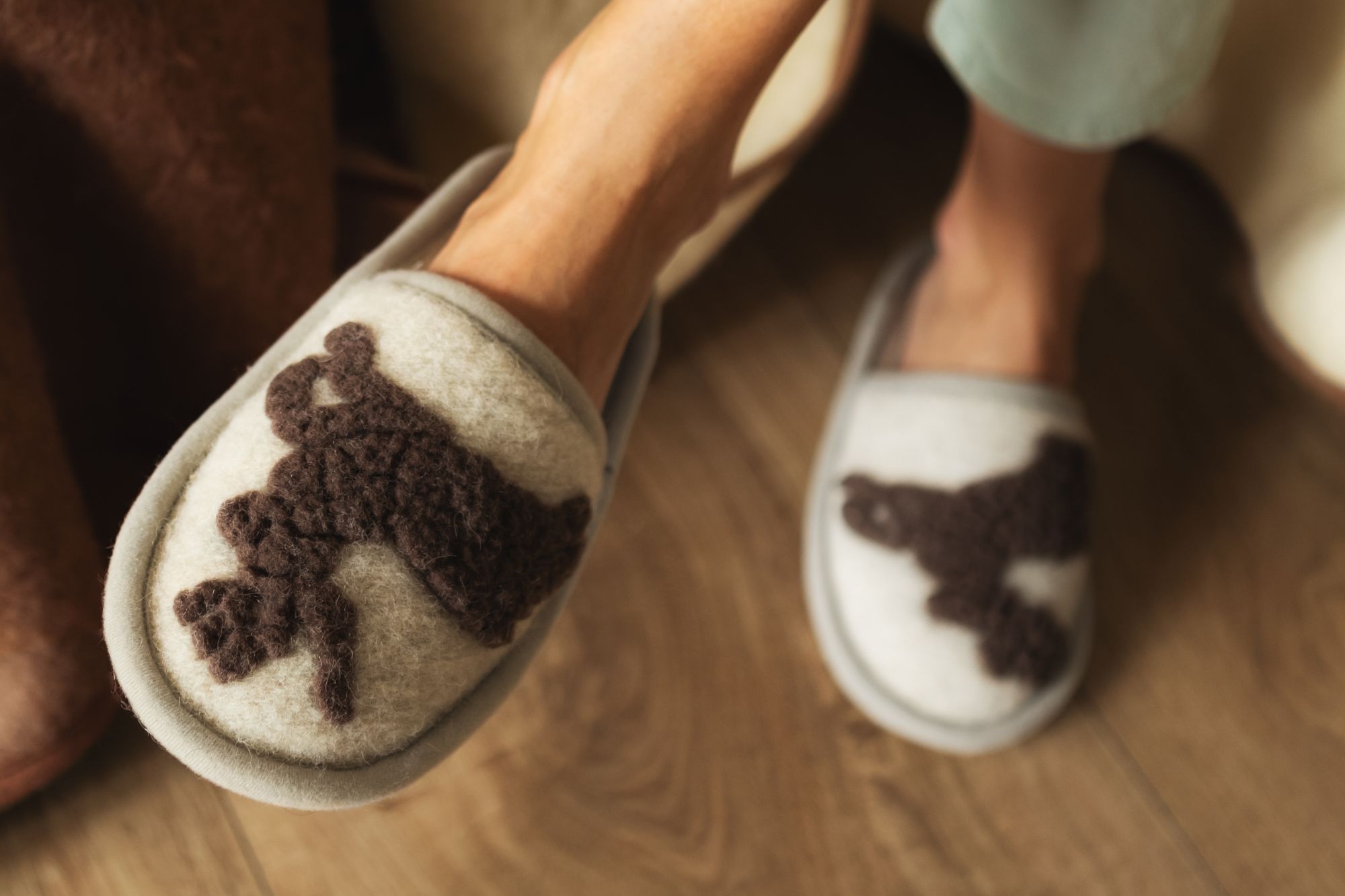 szare kapcie z brązowym wzorem jelonka na tle brązowej podłogi