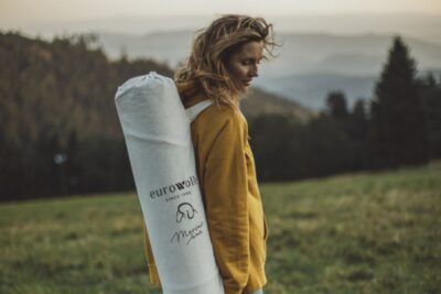 Kobieta w żółtej bluzie z podłużną torbą na plecach w krajobrazie górskim