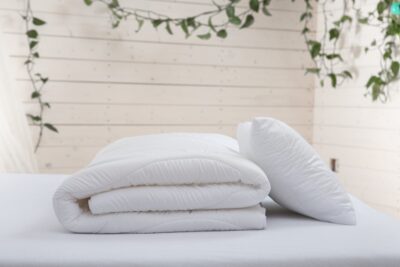 biała kołdra i poduszka z drewnianą ścianą w tle