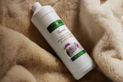 butelka płynu do prania na beżowym tle z wełnianej kołdry