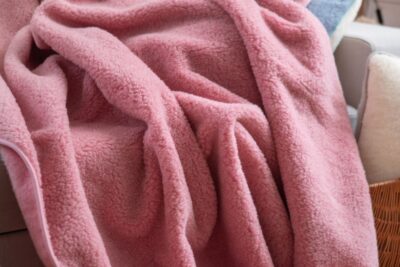 różowy koc wełniany przerzucony na sofie