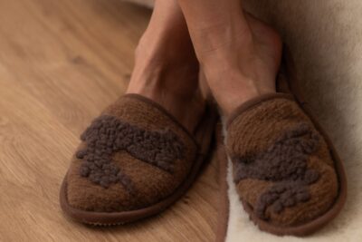 brązowe kapcie z wełny na drewnianej podłodze