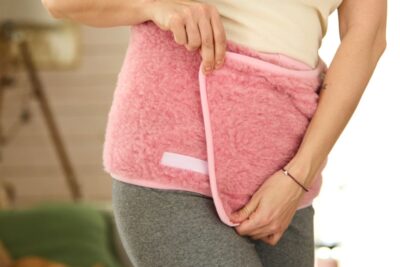 Kobieta zakłada różowy pas lędźwiowy.